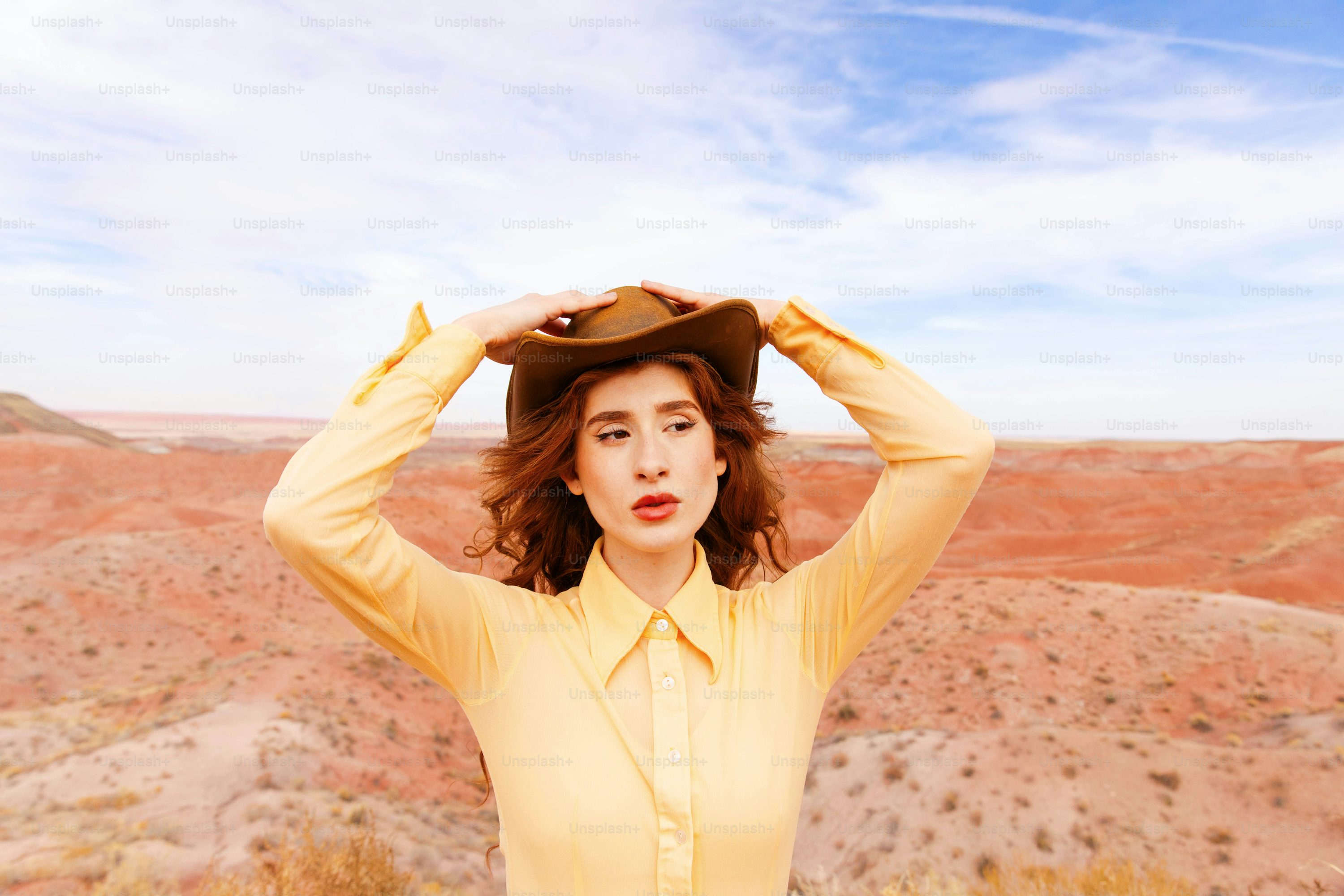 A woman in a yellow shirt is holding a hat